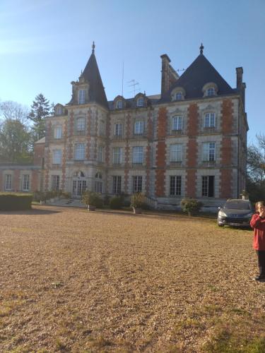 une grande maison avec un enfant debout devant elle dans l'établissement Chateau de rocheux, à Fréteval