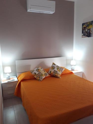 a bedroom with an orange bed with two pillows at Holiday House Marlin in Giardini Naxos