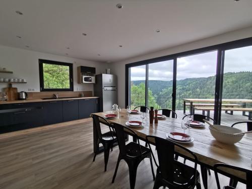 une cuisine et une salle à manger avec une table et des chaises dans l'établissement Maison d'architecte en pleine nature, à Arlempdes
