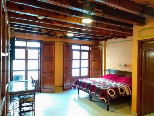 a bedroom with a bed and a table and windows at Cuartel 1914 - Hotel Boutique in Zacatecas