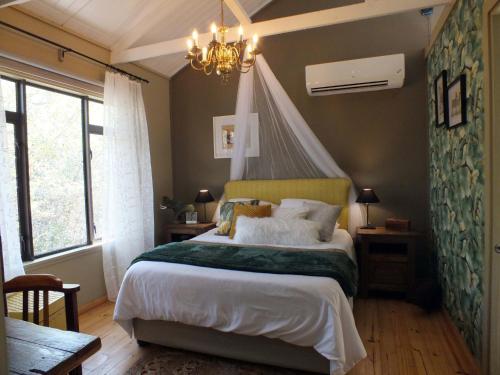 a bedroom with a bed and a chandelier at Pheasant's Crest in Marloth Park