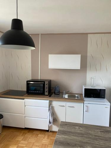 une cuisine avec des armoires blanches et un éclairage noir dans l'établissement Le Rhin et Danube wifi, au Mans