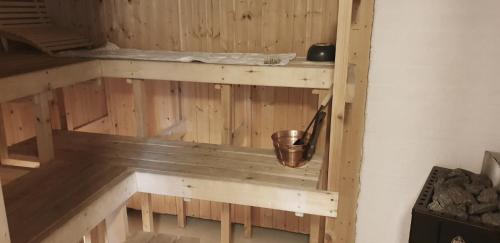 a wooden sauna with a bucket on a shelf at Sydåbacka Guest House, a Room with a Sauna in Kirkkonummi