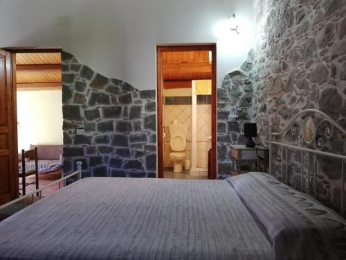 una camera con letto e parete in pietra di Stone house a Montalbano Elicona