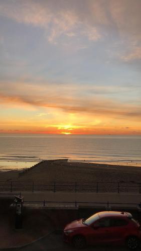a car parked next to the beach with the sunset at Skippers View Sunny Balcony in Eastbourne