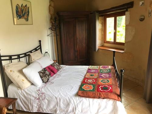 Una cama con una manta encima en un dormitorio. en Chambre d'hôtes Lasserre, en Saint-Amand-de-Coly