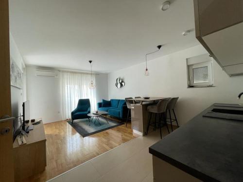 uma cozinha e sala de estar com cadeiras azuis e uma mesa em Apartment MV em Capljina