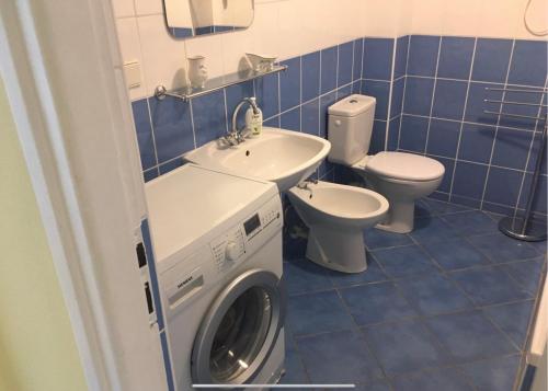 La salle de bains est pourvue de carrelage bleu, d'un lave-linge et de toilettes. dans l'établissement Svahova 986/6, à Karlovy Vary