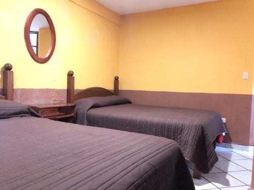 a bedroom with two beds and a mirror on the wall at San Pablo in P&aacute;tzcuaro