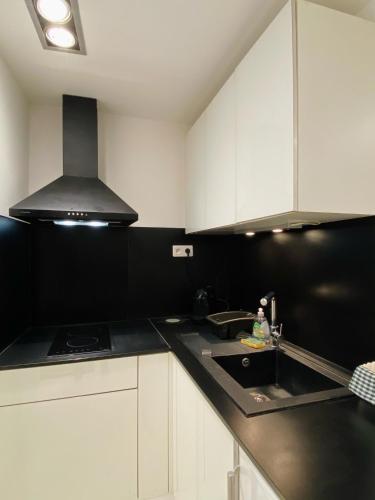 eine Küche mit schwarzen und weißen Schränken und einem Waschbecken in der Unterkunft Studio La Tour in Saint-Étienne-de-Tinée