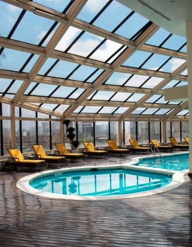 an indoor pool with chairs and a large glass ceiling at MS Milenium Monterrey Curio Collection by Hilton in Monterrey