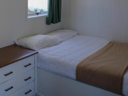 a small bedroom with a bed and a dresser at Holdens Bay Holiday Park in Rotorua