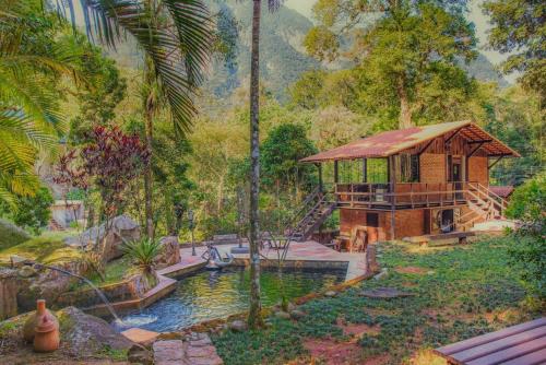 uma pintura de um jardim com uma casa e um lago em Sitio na Serra dos Orgaos com rio de aguas cristalinas em Guapimirim