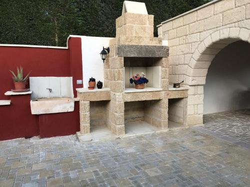 ルッファーノにあるCasa Vacanza da Giò con PISCINA PRIVATAの赤壁の中庭の石造りの暖炉