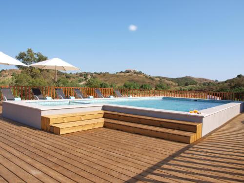 a swimming pool on a wooden deck with chairs around it at Quinta de São Gabriel in Castro Marim