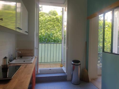 une cuisine avec un évier et une porte donnant sur un balcon. dans l'établissement Cosy appartement familial au coeur de marseille, à Marseille