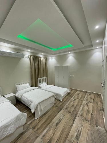 1 dormitorio con 2 camas y luz verde en شاليهات البارو, en Yeda