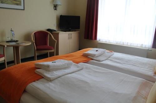 two beds in a hotel room with towels on them at Hotel & Restaurant Zum Kap Arkona in Putgarten