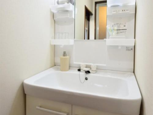 een badkamer met een witte wastafel en een spiegel bij Kasuian in Kyoto