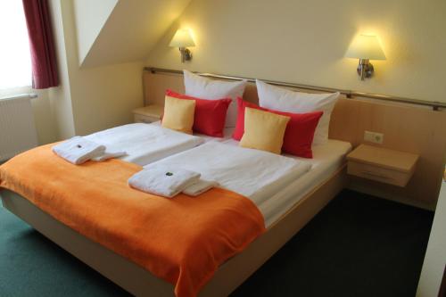 a bedroom with a large bed with red and yellow pillows at Hotel & Restaurant Zum Kap Arkona in Putgarten