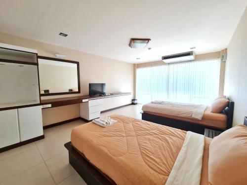a hotel room with two beds and a flat screen tv at โรงแรม ชาโตว์วิสต้า in Chon Buri