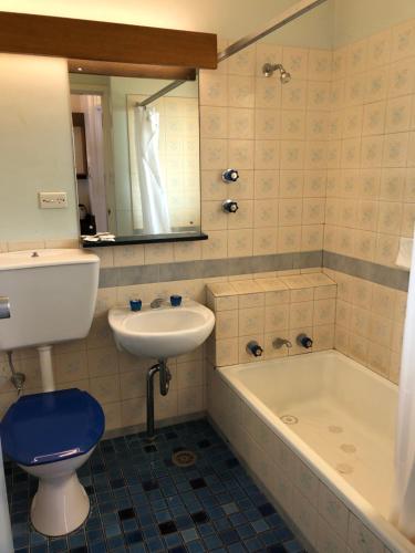 y baño con lavabo, bañera y aseo. en Canberra Lyneham Motor Inn, en Canberra