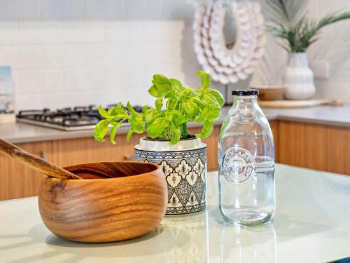 a glass table with a plant and a bottle of water at Catch of the Bay by Experience Jervis Bay in Vincentia