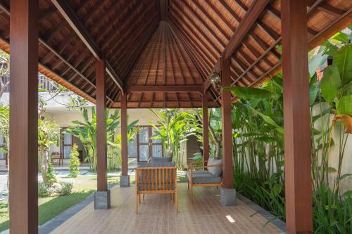 a pavilion with a table and chairs in a garden at Mupu Jana G.House Keramas in Keramas