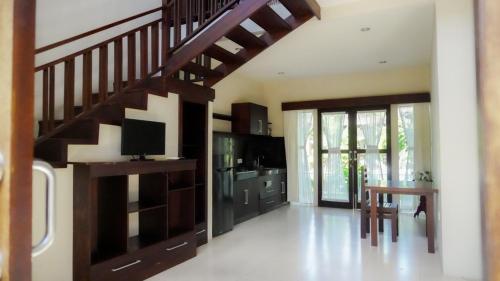 a living room with a wooden staircase with a television at The Janan Villa in Sanur