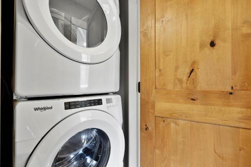 a washing machine sitting next to a wooden door at Spacious Modern Ski-in Ski-out with Hot Tub Townhouse in Sun Peaks