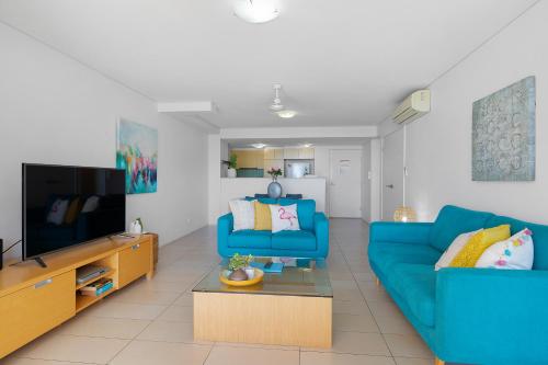 a living room with a blue couch and a tv at Azure Sea Whitsunday Resort in Airlie Beach