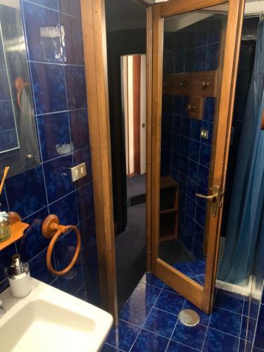 La salle de bains est pourvue d'un lavabo et d'une douche avec du carrelage bleu. dans l'établissement Appartamento BREUIL CERVINIA, à Breuil-Cervinia