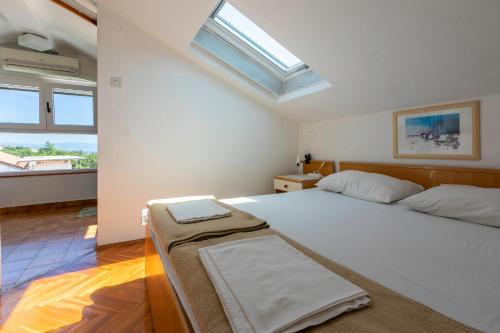 a bedroom with a large white bed and windows at Apartments Rozaria in Dramalj