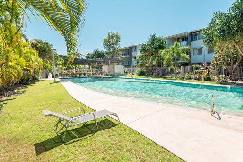 a swimming pool with a bench next to a building at Ramada Encore by Wyndham Whale Cove in Hervey Bay