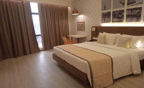 a hotel room with a large bed and a window at The Avatar Hotel & Convention in Mangalore