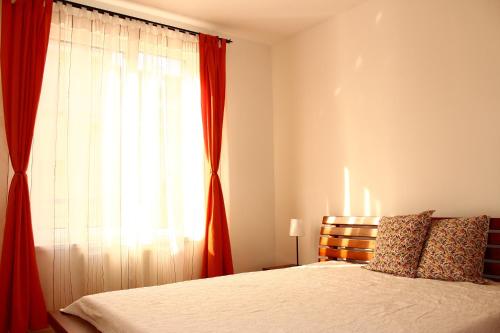 a bedroom with a bed and a window with red curtains at Blanca Apartman in Budapest