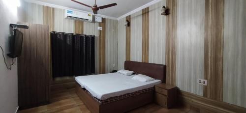 a small bedroom with a bed and a mirror at Hotel Samrat in Dehradun