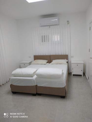 a bedroom with two beds in a white room at נופש במושב in Ẕafriyya