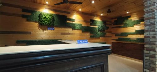a bar with green plants on a wooden wall at Hotel Samrat in Dehradun