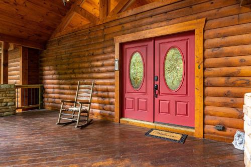 eine rote Tür in einem Blockhaus mit einem Stuhl in der Unterkunft Now and Forever cabin in Sevierville