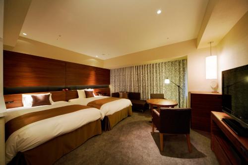 a hotel room with two beds and a flat screen tv at Hotel Metropolitan Akita in Akita