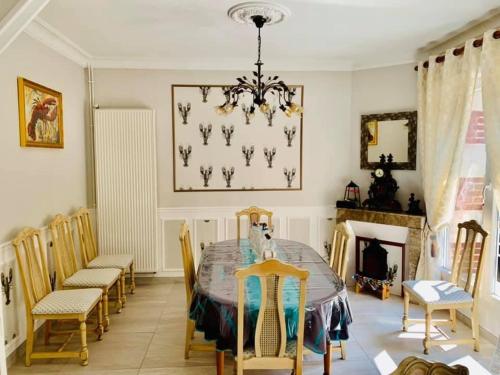 une salle à manger avec une table, des chaises et un lustre dans l'établissement La Homardine, à Monchy-Saint-Éloi