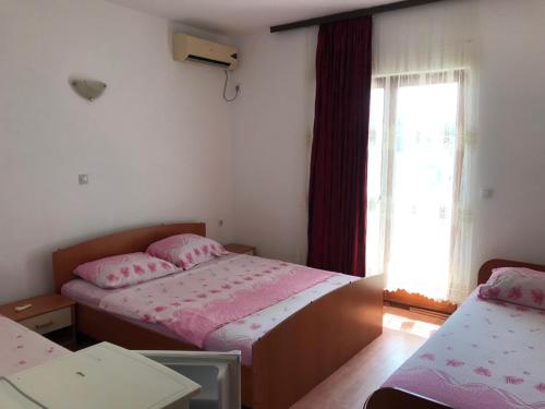 1 dormitorio con 2 camas y ventana en Rooms Ajllin, en Ulcinj