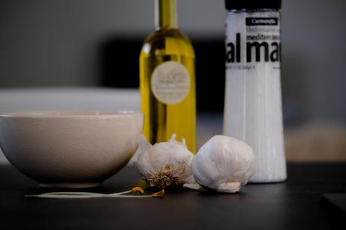 a bottle of wine and a bowl and garlic on a table at Appartementen Zer en Loft in centrum Bergen in Bergen