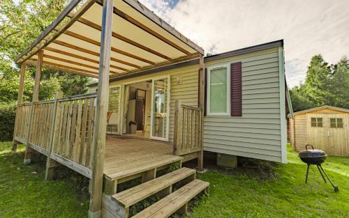 a tiny house with a porch and a grill at Camping du Château Vert in Hondainville
