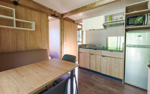 a small kitchen with a table and a refrigerator at Camping du Château Vert in Hondainville