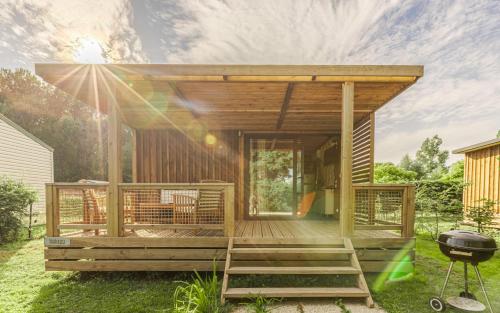 a house with a deck with a grill in a yard at Camping du Château Vert in Hondainville