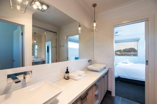 baño con lavabo, espejo y cama en Mandel on High - Echuca Holiday Homes en Echuca