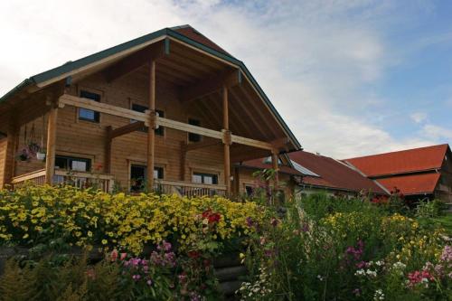 a large wooden house with flowers in front of it at Ferienwohnungen am Bio-Bauernhof Herdengl in Lunz am See