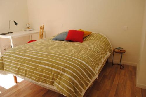 a bed with a yellow and red pillow on it at Appartement dans bâtiment du 18ème siècle in Argentan